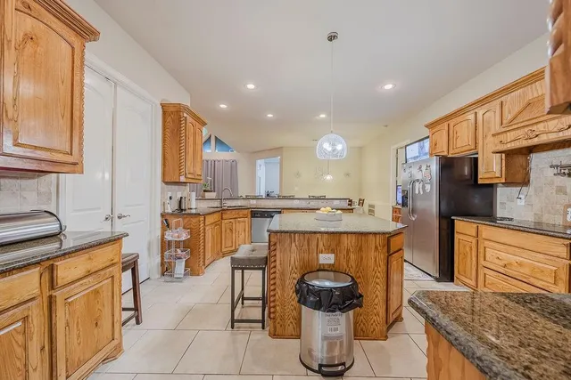 a kitchen with kitchen island granite countertop wooden cabinets and white appliances