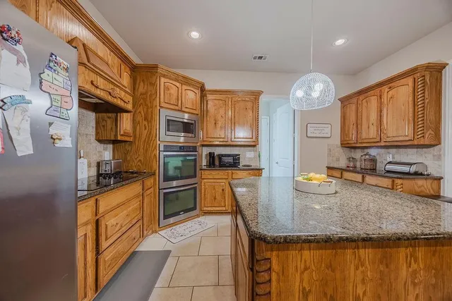 a kitchen with stainless steel appliances granite countertop a sink dishwasher stove and refrigerator