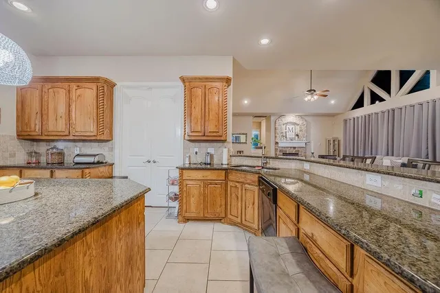 a large kitchen with granite countertop a sink a counter top space and cabinets