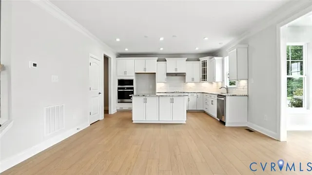 a large white kitchen with white cabinets and stainless steel appliances