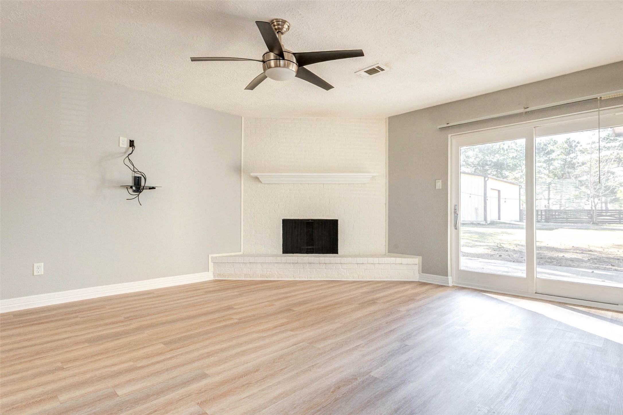 18526 Fenske Road Cypress, TX 77433 - Photo 9 of 32 The inviting living room showcases a fireplace with a white brick surround extending to the ceiling. A dedicated media wall provides space for a television and equipment, and sliding glass doors lead to the backyard while bringing in natural light and views.