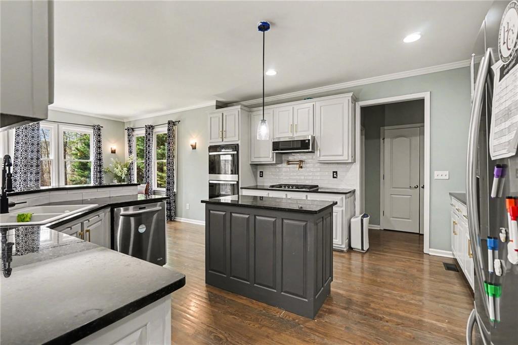 1958 Mapmaker Drive Northeast Dacula, GA 30019 - Photo 12 of 35 a kitchen with kitchen island granite countertop a sink appliances cabinets and a counter top space