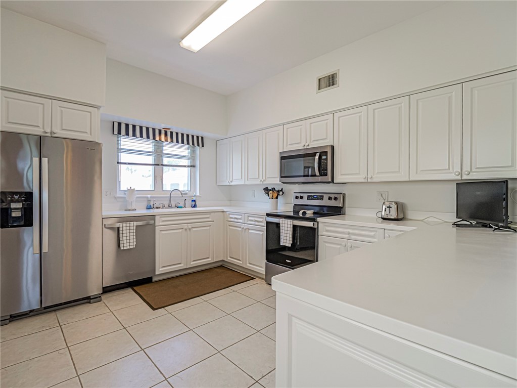 5035 Harmony Circle, Unit 101 Vero Beach, FL 32967 - Photo 11 of 36 a kitchen with white cabinets and white appliances