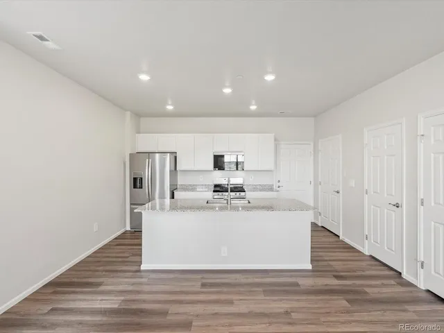 a large white kitchen with kitchen island a sink and a refrigerator