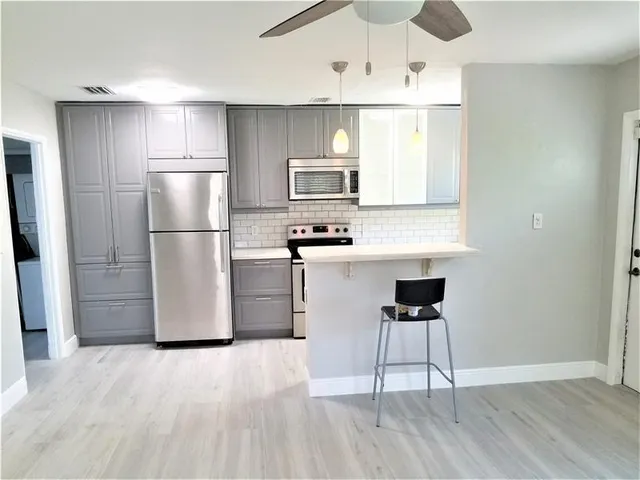 a kitchen with kitchen island white cabinets and stainless steel appliances