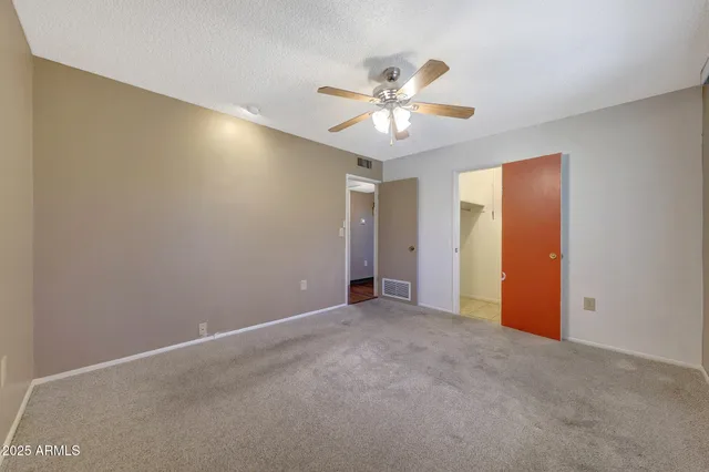 an empty room with closet and a chandelier fan