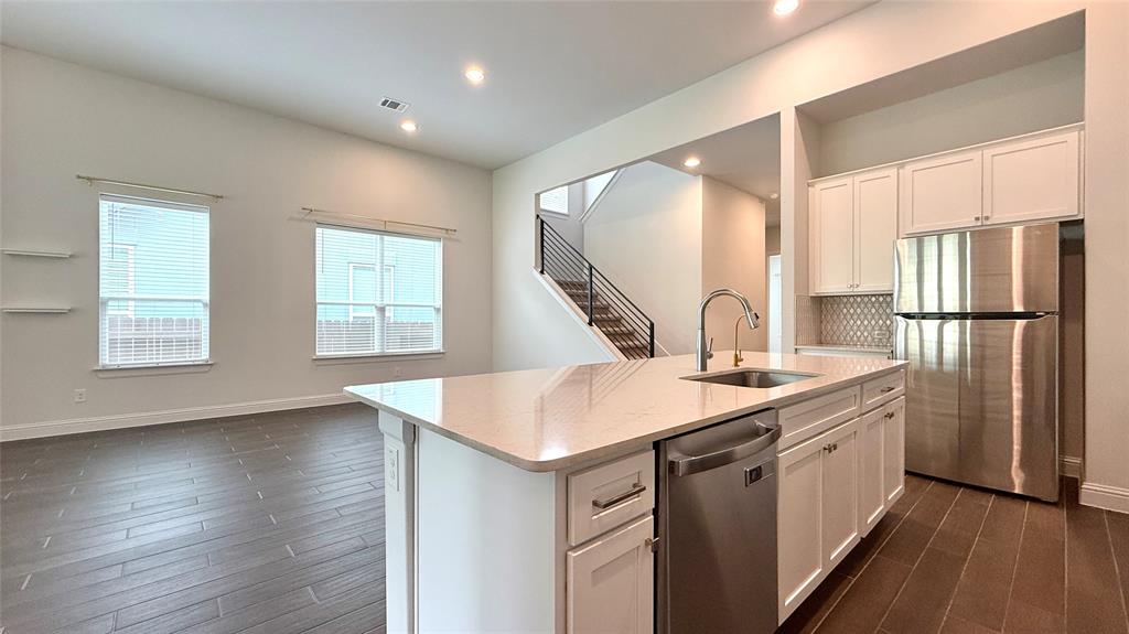 601 C-Bar Ranch Trail, Unit 27 Cedar Park, TX 78613 - Photo 4 of 29 Open-concept living space featuring a modern kitchen island with an undermount sink, quartz countertops, and stainless steel appliances