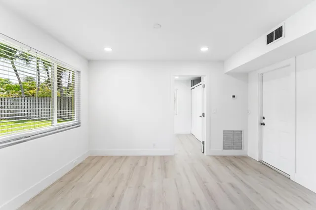 a view of an empty room with wooden floor and a window