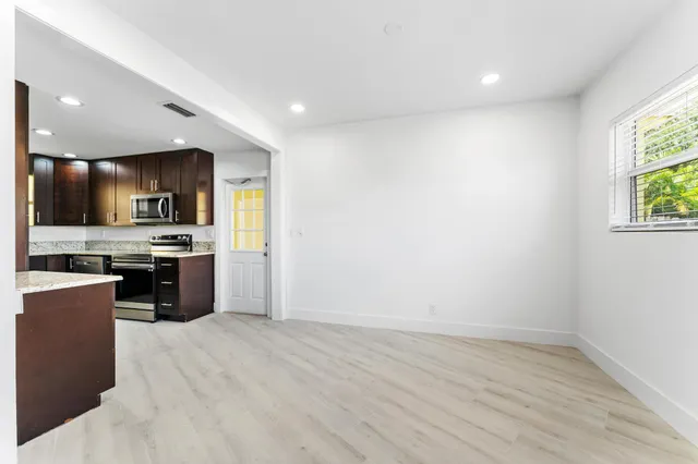 a kitchen with granite countertop a stove top oven a sink dishwasher a dining table and chairs with wooden floor