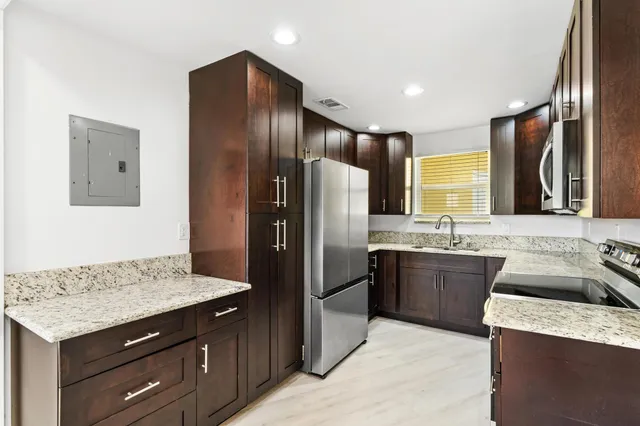 a kitchen with granite countertop stainless steel appliances a sink stove and refrigerator