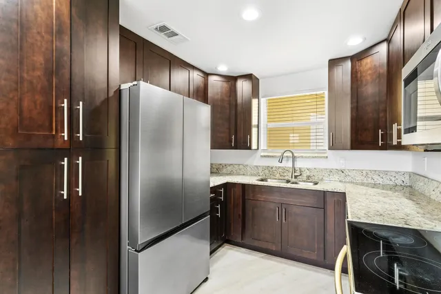 a kitchen with stainless steel appliances granite countertop a refrigerator and a sink