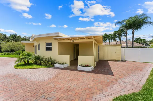 a front view of a house with a yard and potted plants