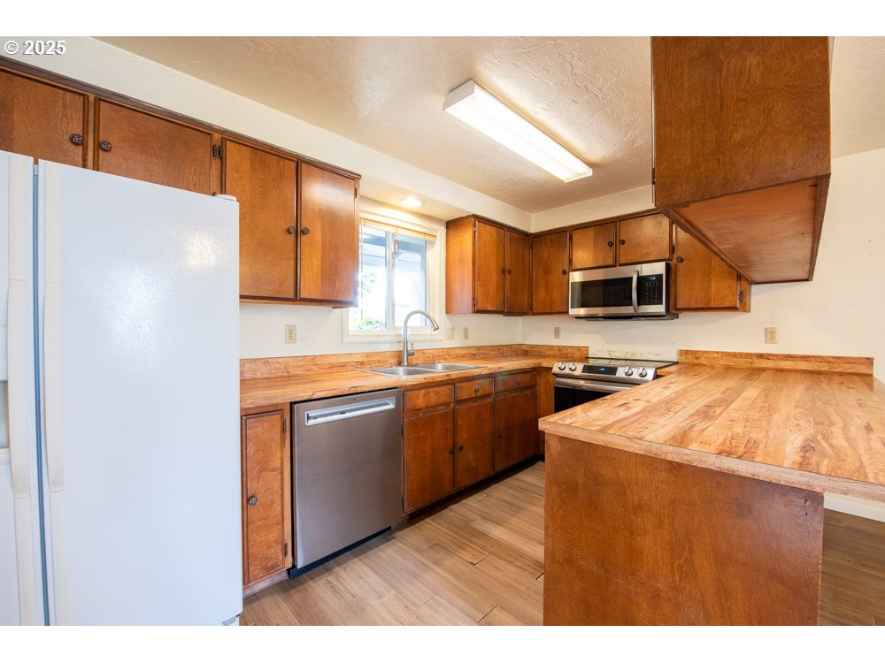 4631 Daisy Street Springfield, OR 97478 - Photo 11 of 46 a kitchen with stainless steel appliances granite countertop a sink a stove a refrigerator with grey cabinets