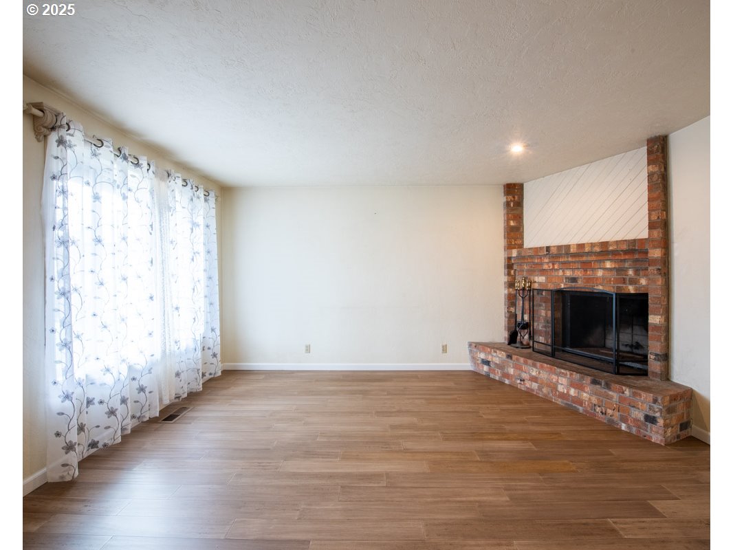 4631 Daisy Street Springfield, OR 97478 - Photo 6 of 46 a view of empty room with wooden floor and fireplace