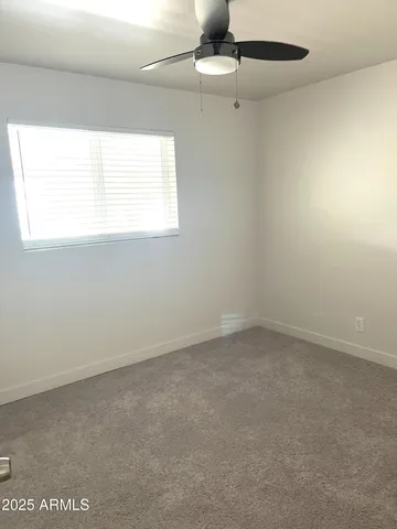 an empty room with a window and a ceiling fan