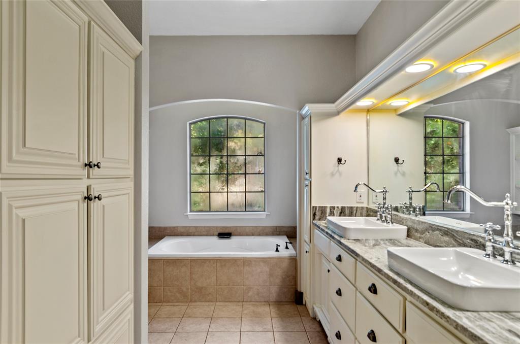 396 Ranchview Court Bowie, TX 76230 - Photo 13 of 38 a bathroom with a granite countertop bathtub a sink and a mirror