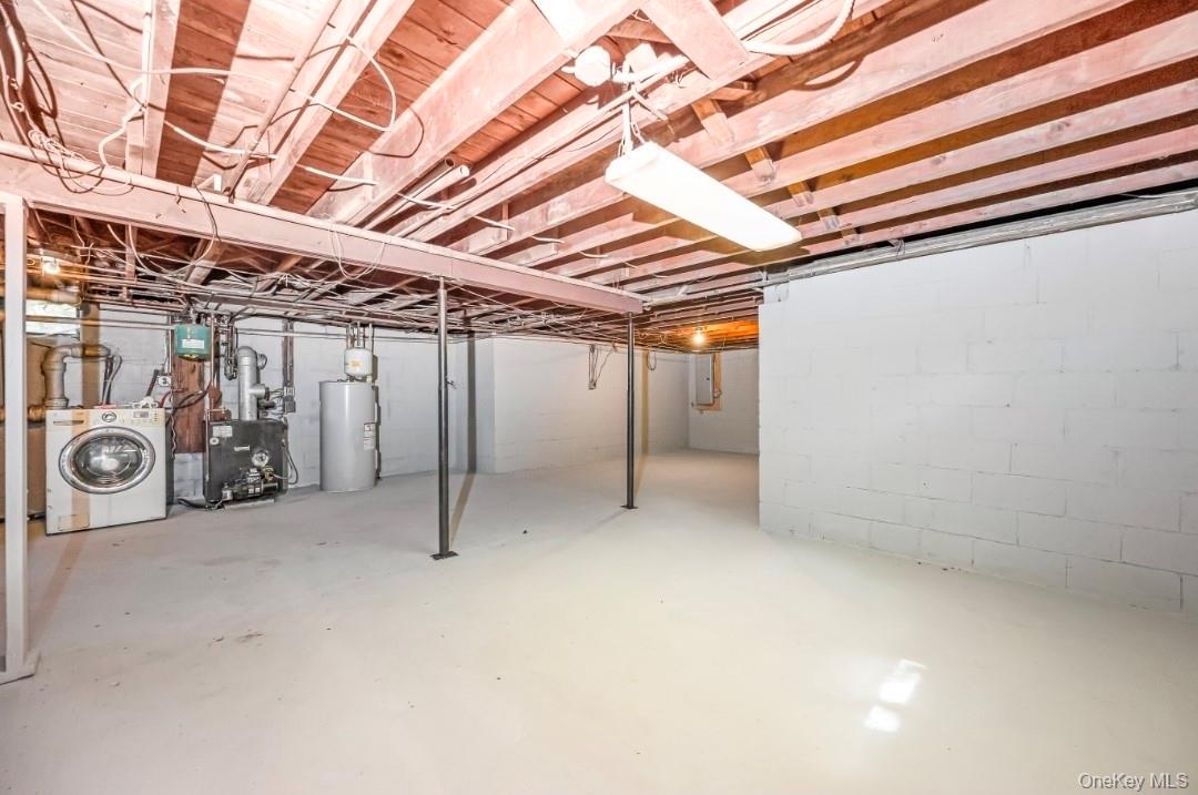 9 Half Moon Pond Road Ridge, NY 11961 - Photo 20 of 26 Unfinished basement featuring exposed wood ceiling joists, concrete block walls, and a concrete floor