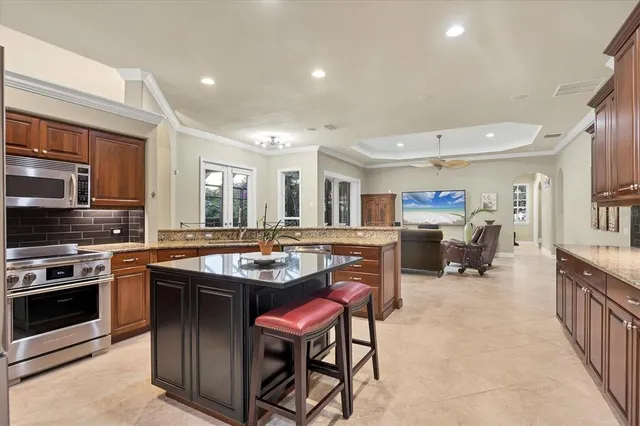 a kitchen with stainless steel appliances granite countertop a stove top oven a sink dishwasher a dining table and chairs with wooden floor