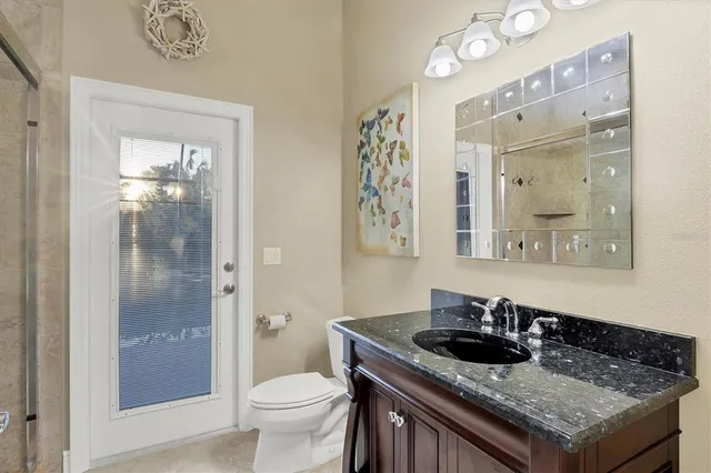 a bathroom with a granite countertop sink a toilet a mirror and shower