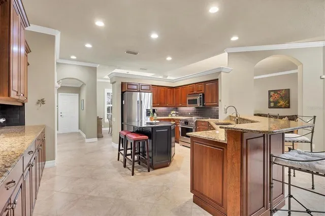 a kitchen with a sink refrigerator and chairs