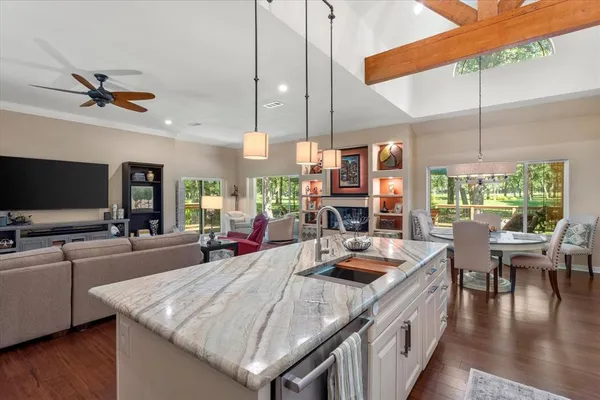 a kitchen with stainless steel appliances granite countertop a sink a counter space and living room view