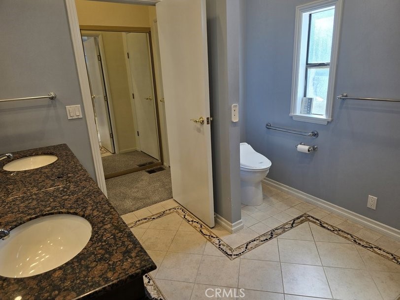 12618 3rd Street, Unit 63 Yucaipa, CA 92399 - Photo 49 of 65 a bathroom with a granite countertop sink a toilet and a mirror