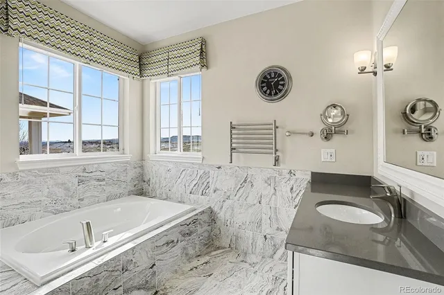 a bathroom with a granite countertop sink and a bathtub