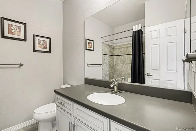 a bathroom with a granite countertop sink toilet a mirror and shower