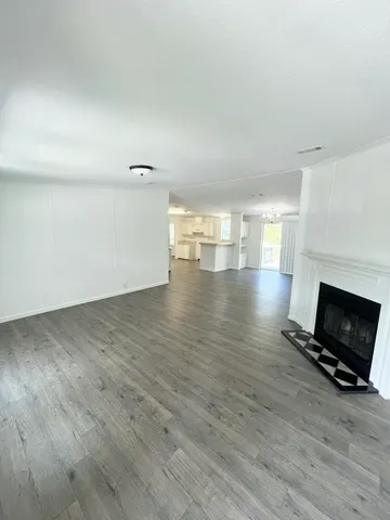 a view of empty room with wooden floor and fireplace