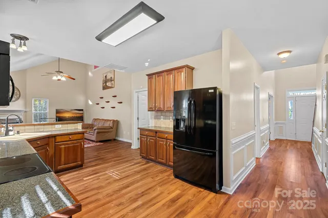 a kitchen with granite countertop stainless steel appliances a refrigerator cabinets and wooden floor