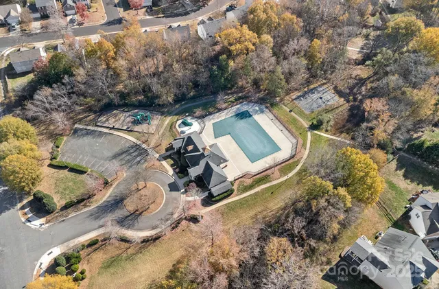 an aerial view of a house with swimming pool and large trees