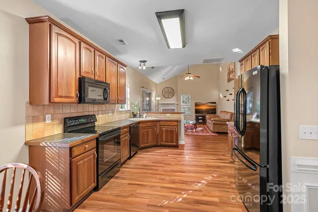 a kitchen with stainless steel appliances granite countertop a stove top oven a sink dishwasher a refrigerator and cabinets with wooden floor