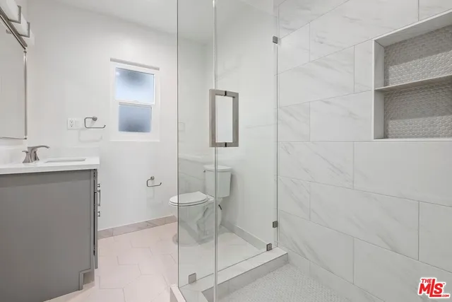 a bathroom with a granite countertop sink a toilet and shower
