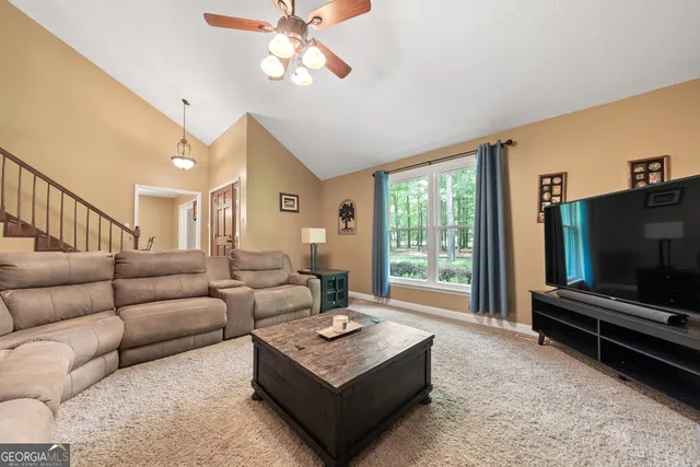 a living room with furniture a flat screen tv and a large window
