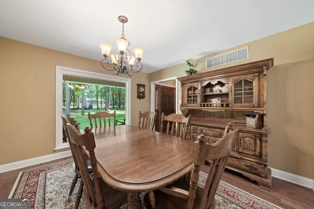 a view of a dining room with furniture a chandelier and wooden floor