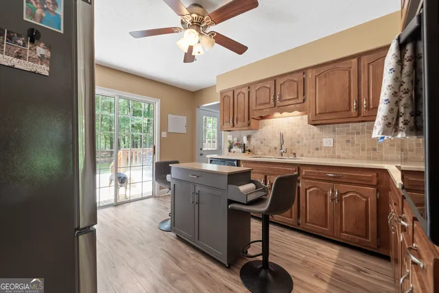 a kitchen with kitchen island granite countertop a table chairs a sink dishwasher refrigerator and cabinets