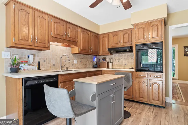 a kitchen with stainless steel appliances granite countertop a sink a stove a refrigerator cabinets and wooden floor