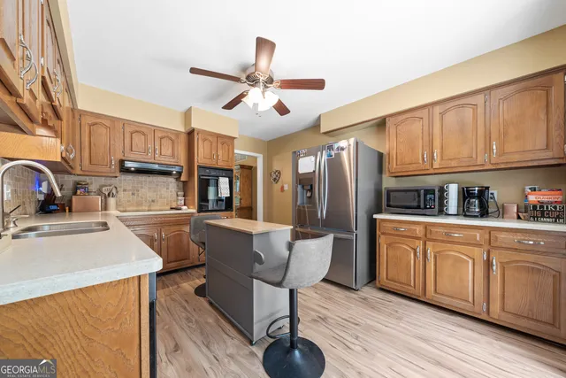 a kitchen with stainless steel appliances granite countertop a refrigerator a sink dishwasher a stove and white countertops with wooden floor