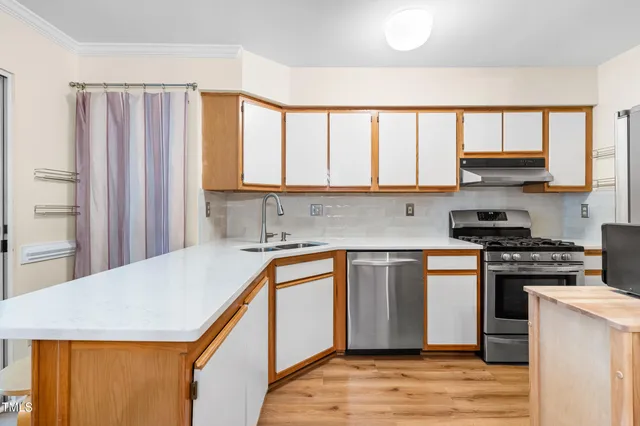 a kitchen with stainless steel appliances granite countertop a sink a stove and a wooden cabinets