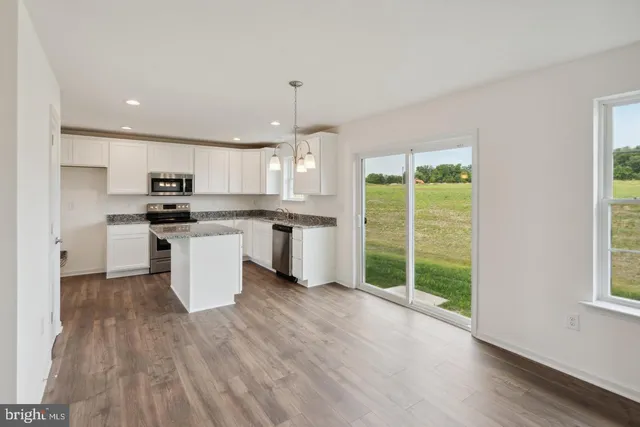 a kitchen with stainless steel appliances granite countertop a stove top oven a sink dishwasher a refrigerator and white cabinets with wooden floor