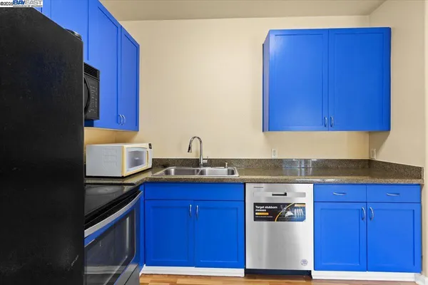 a kitchen with granite countertop wood cabinets stainless steel appliances and a sink