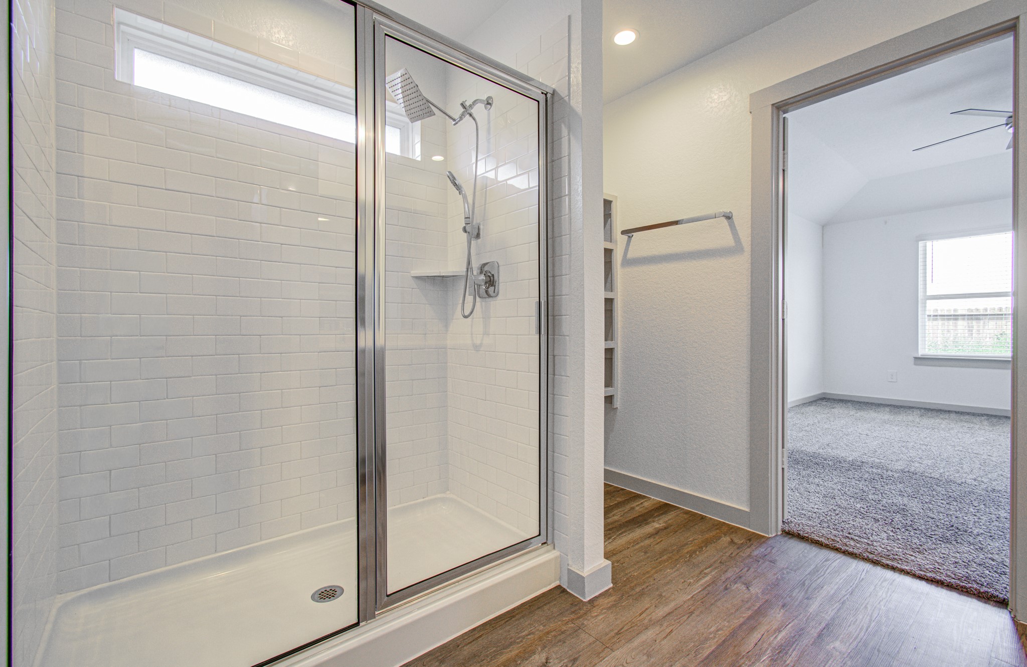 7903 Wrangler Shack Lane Rosharon, TX 77583 - Photo 27 of 29 Discover a sleek, modern bathroom with a glass-enclosed shower and white tile, seamlessly leading to a bright bedroom with plush carpet, all bathed in natural light and exuding contemporary elegance.