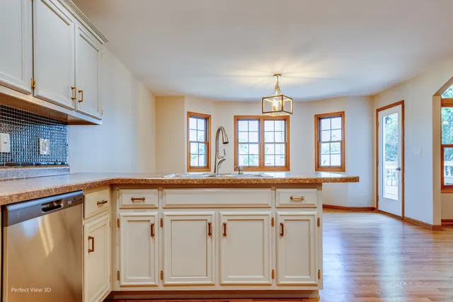 a spacious kitchen with granite countertop a stove a sink and dishwasher with wooden floor