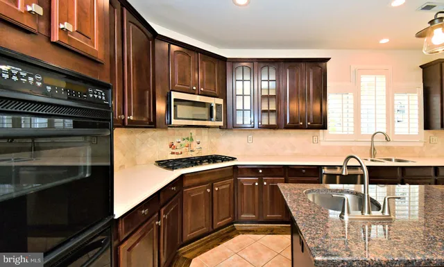 a kitchen with stainless steel appliances granite countertop a sink a refrigerator and a granite counter tops