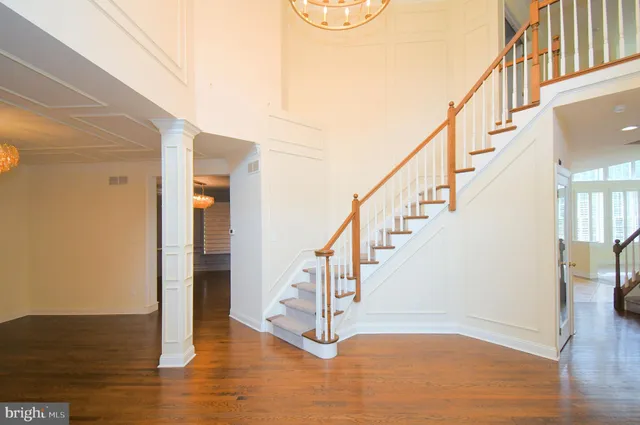 an empty room with wooden floor chandelier and windows