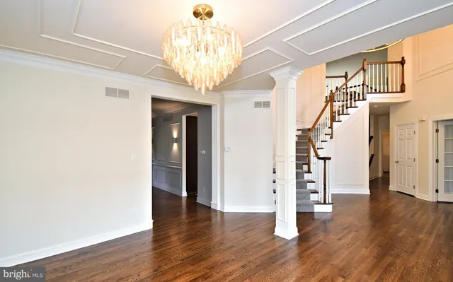 a view of a hallway with wooden floor and chandelier
