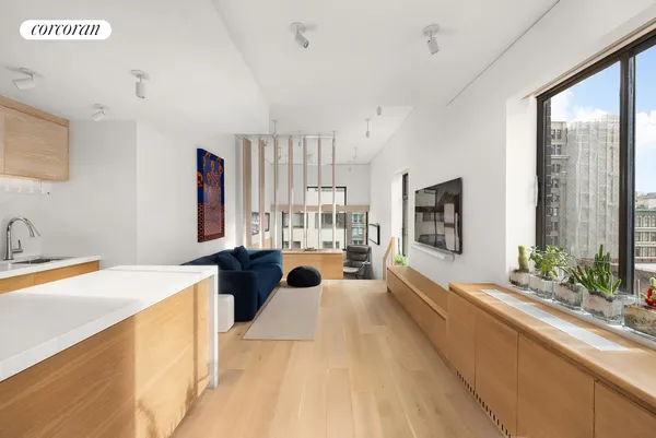 a large living room with stainless steel appliances furniture a large window and a kitchen view