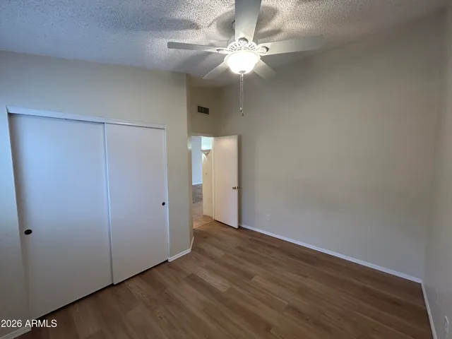 an empty room with wooden floor and fan