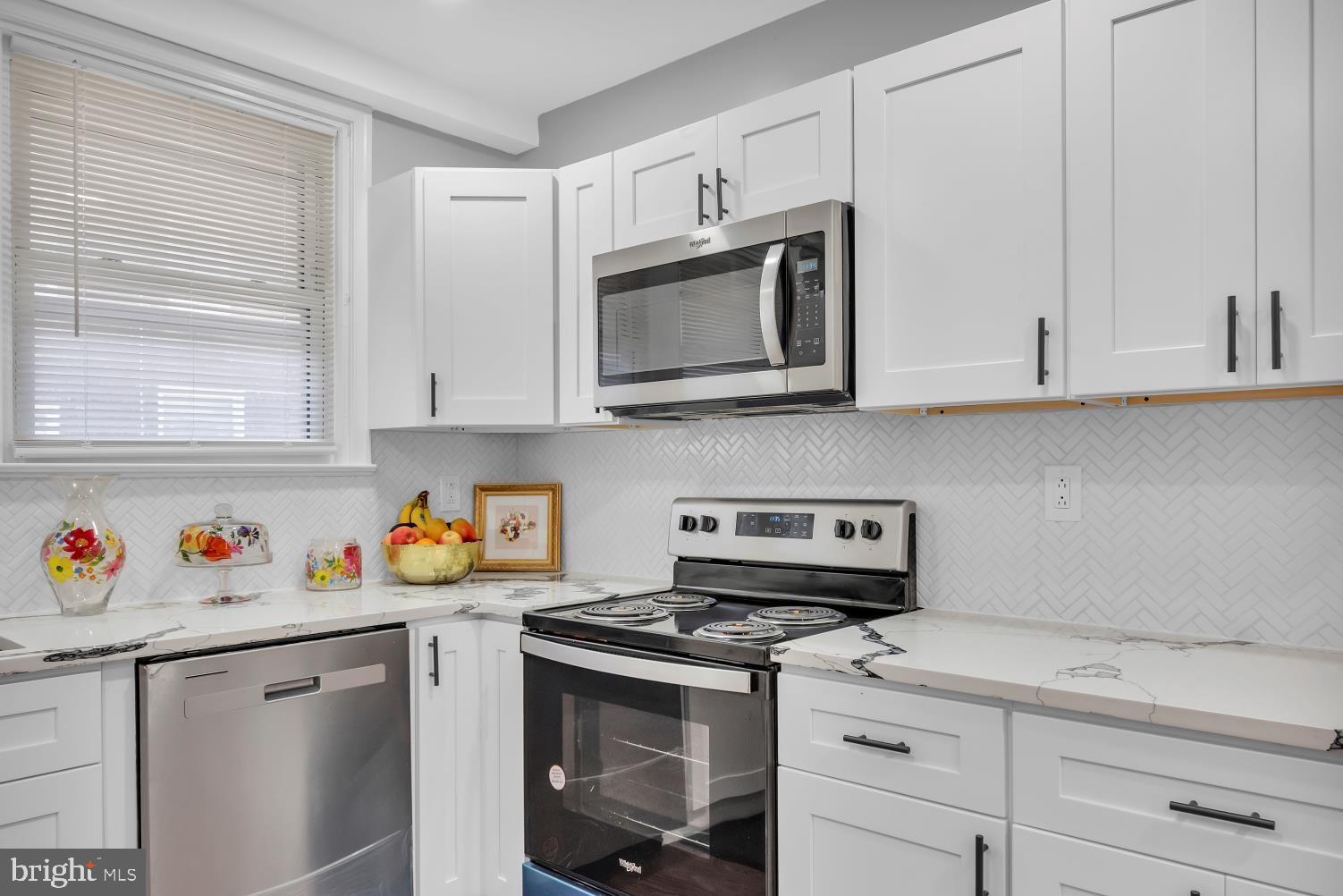 a kitchen with stainless steel appliances granite countertop white cabinets stove top oven and granite counter top