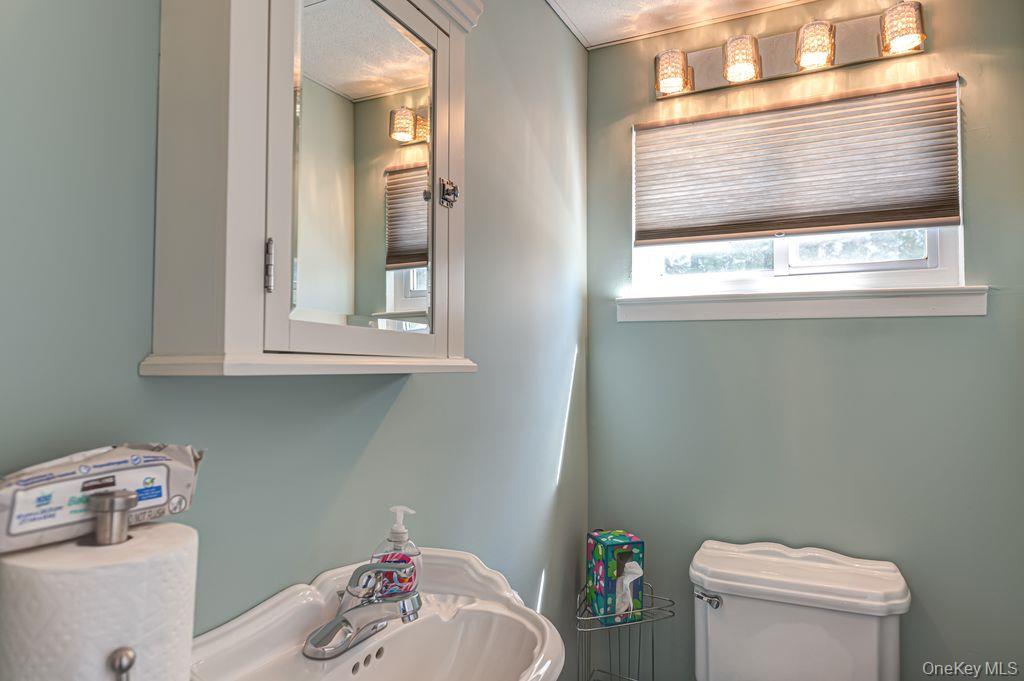 89 Cheltenham Road West Babylon, NY 11704 - Photo 11 of 26 a bathroom with a toilet sink and mirror